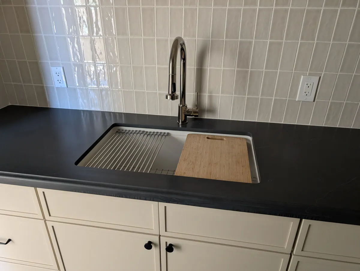 Modern kitchen sink with chrome pull-down faucet on black quartz countertop, Prescott